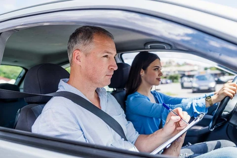 Scène extérieure avec véhicule d'auto-école stationné, instructeur visible à l'intérieur du véhicule de formation à la conduite