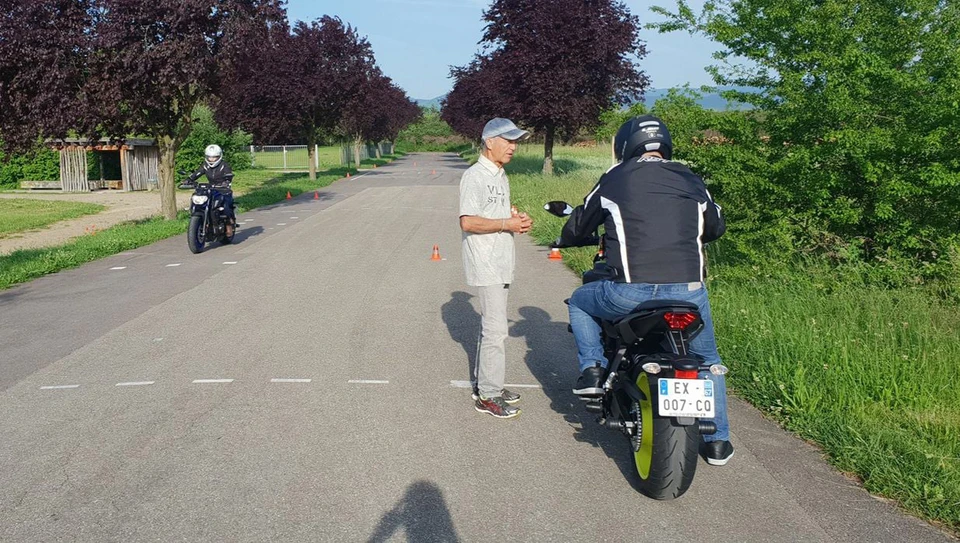 Motocycliste en équipement de protection sur circuit d'entraînement extérieur, naviguant entre cônes de signalisation orange